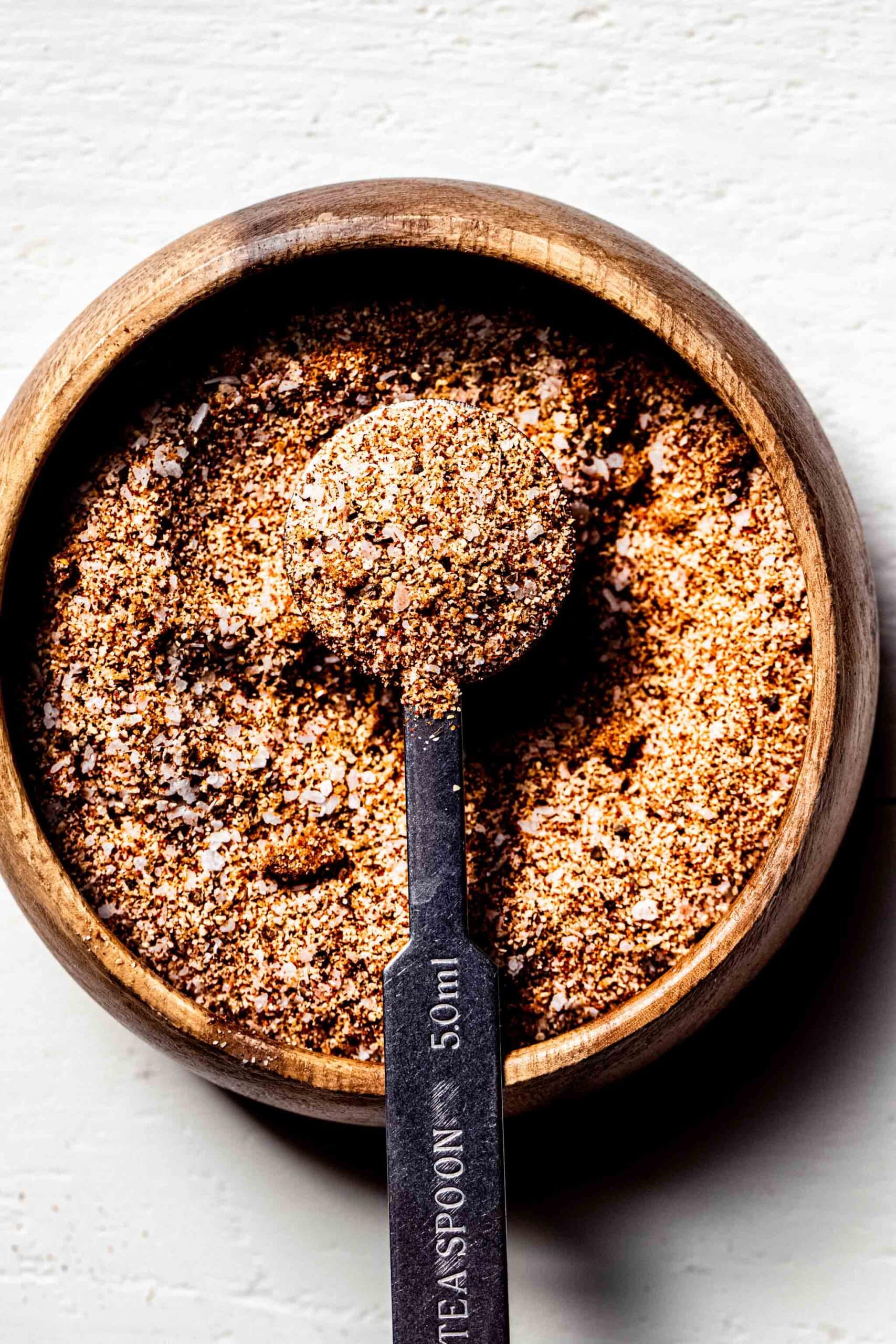 Tri tip dry rub in small wooden bowl with teaspoon.