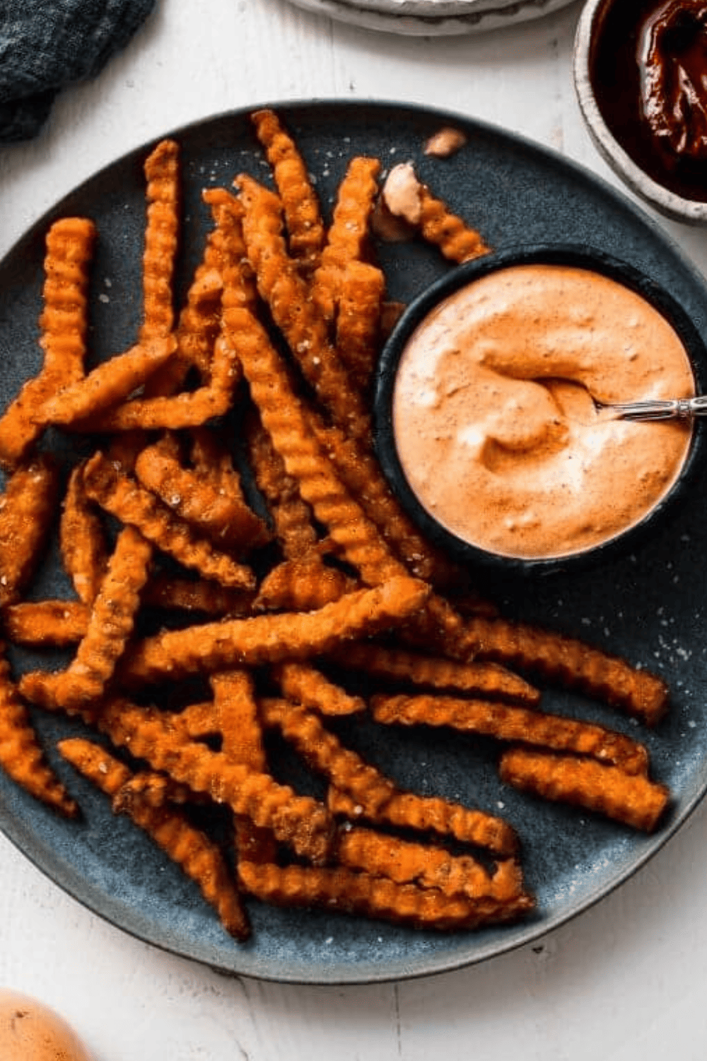 Small bowl of dipping sauce on plate of sweet potato fries.