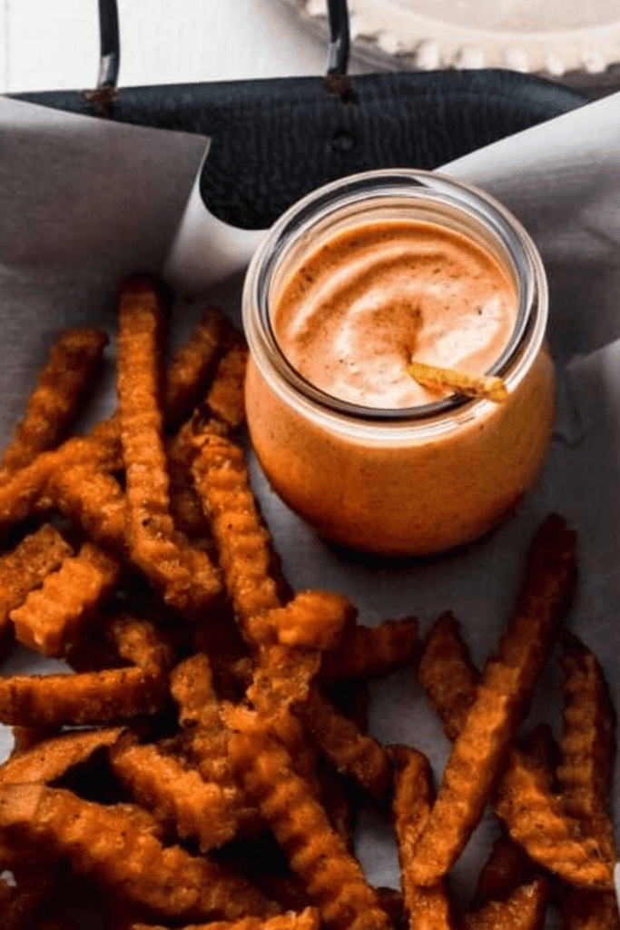 Sauce in small jar on platter of fries. 