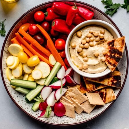 Hummus on platter with veggies and crackers.
