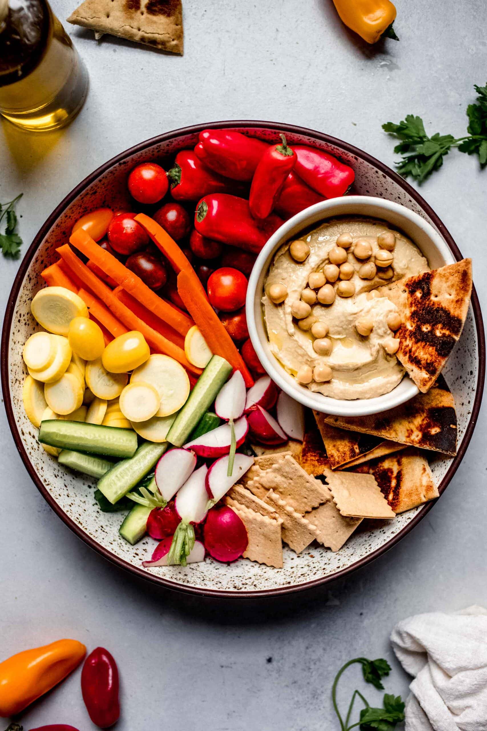 Hummus on platter with veggies and crackers.