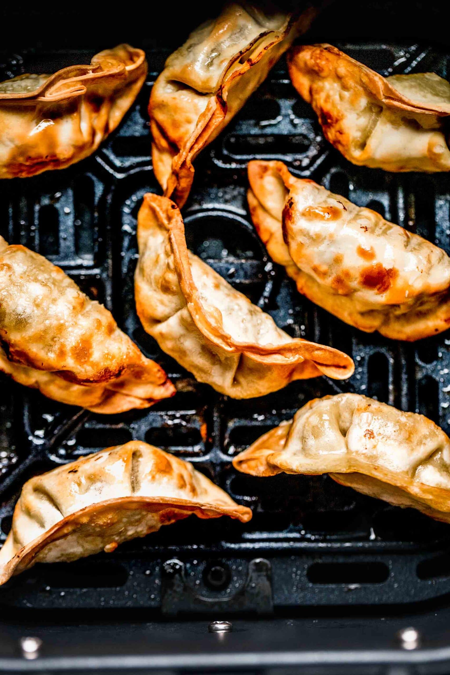 Cooked potstickers in air fryer basket.