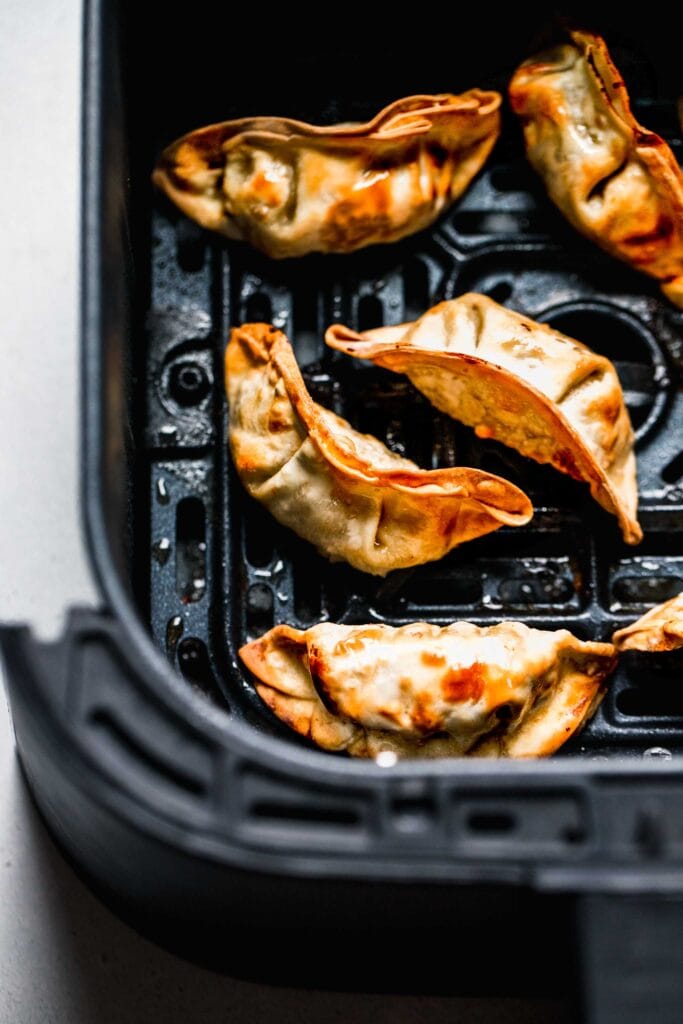 Cooked potstickers in air fryer basket. 