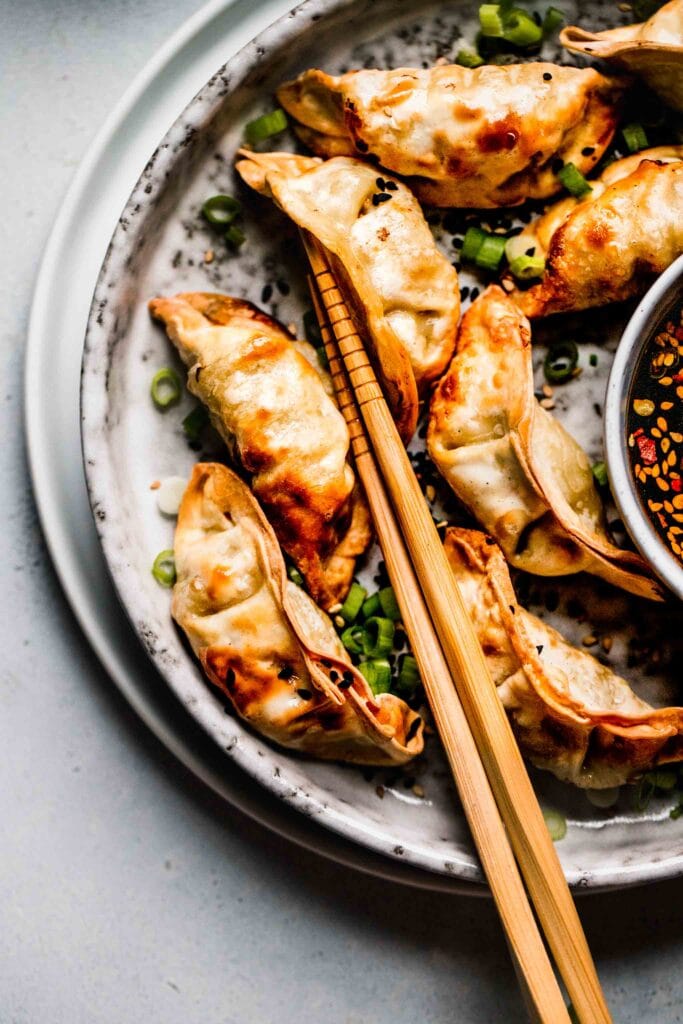 Cooked potstickers on plate with chopsticks. 