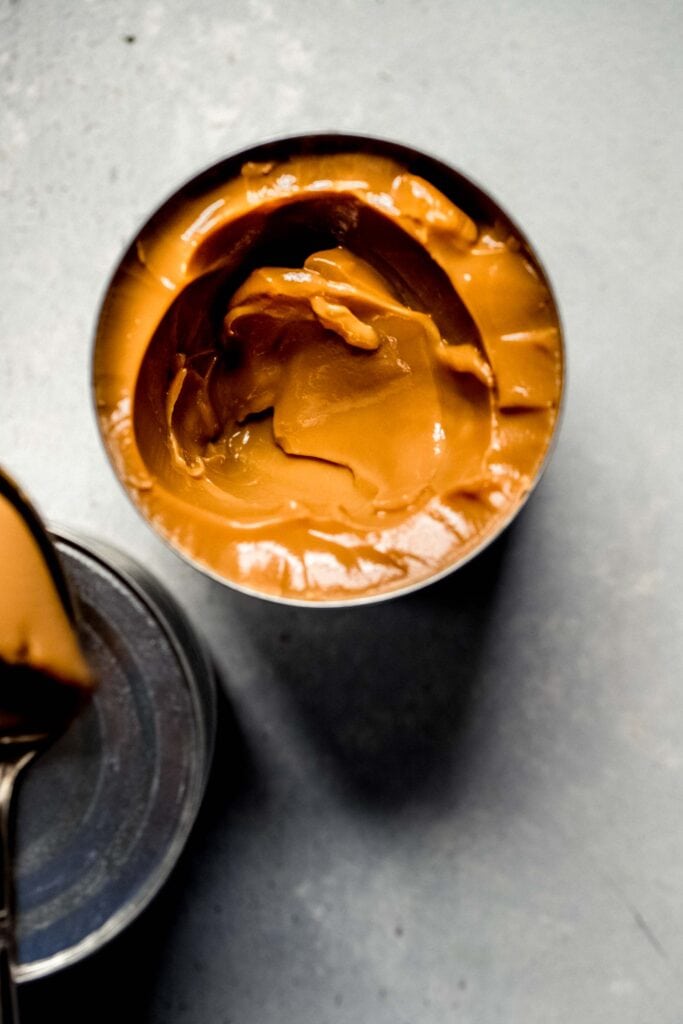 Can of dulce de leche with scoop out of it. 
