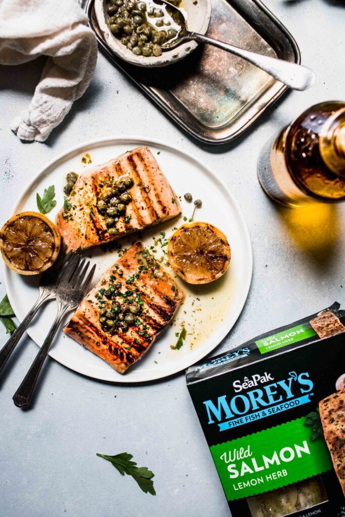 Pack of Morey's fish filets next to plate of grilled salmon. 