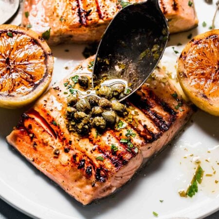 Lemon butter sauce being spooned on salmon.