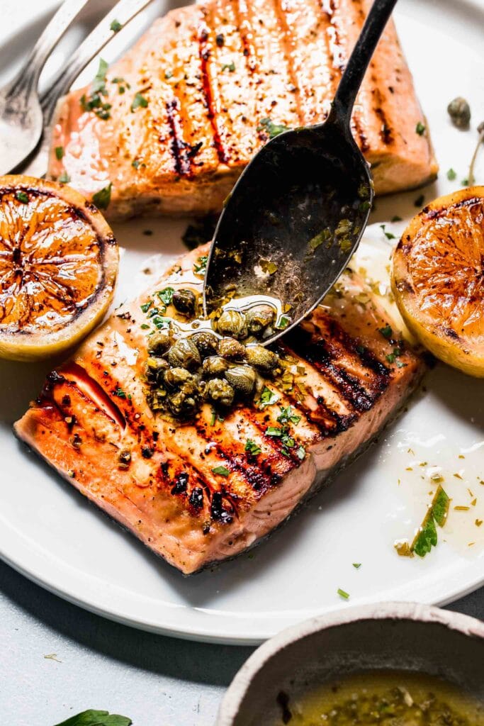 Lemon butter sauce being spooned on salmon.