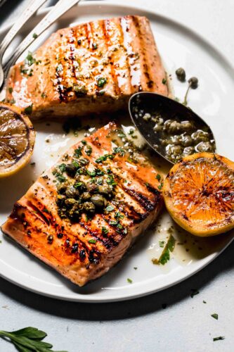 Salmon filets on plate with spoon of caper sauce.