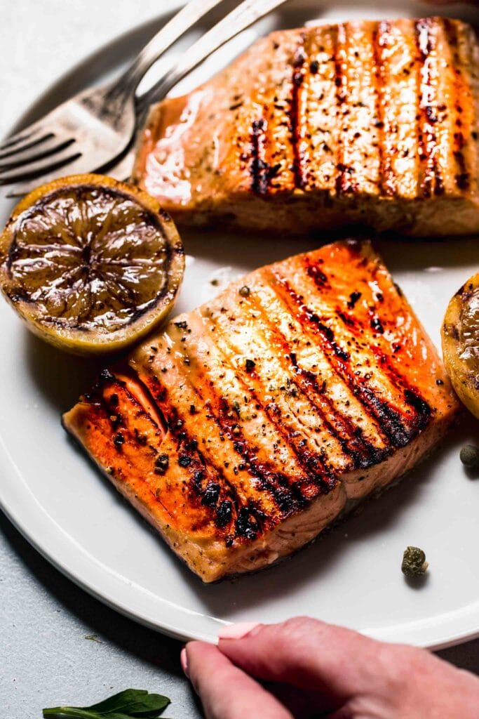 Grilled salmon filets on plate with charred lemon. 