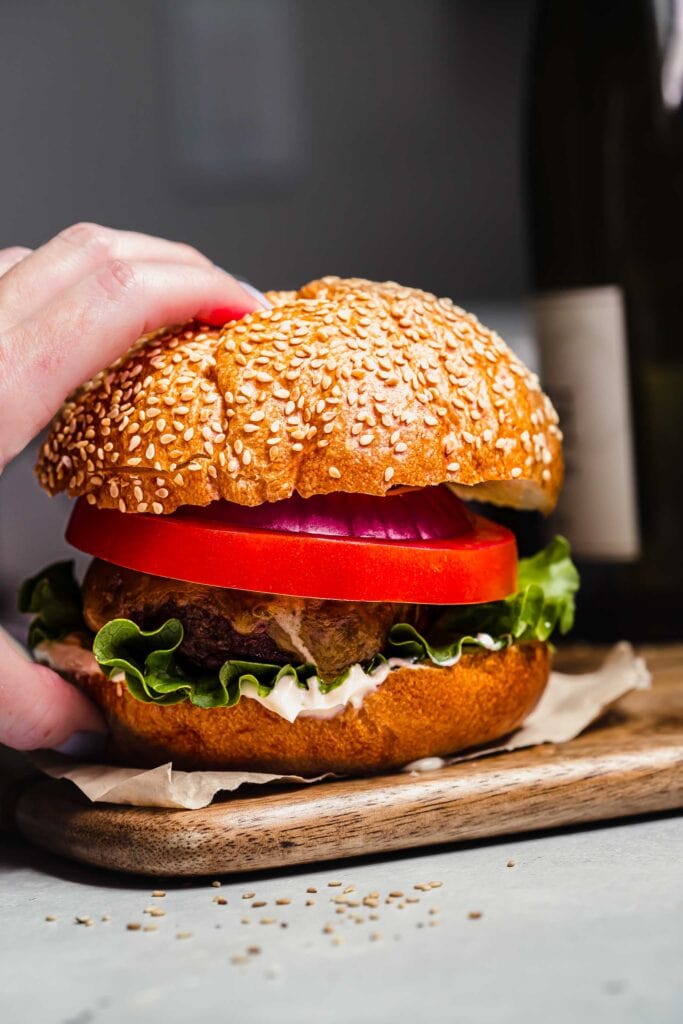Hand holding smoked burger.