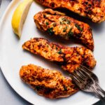 Sous vide chicken tenders on plate with lemon wedges.