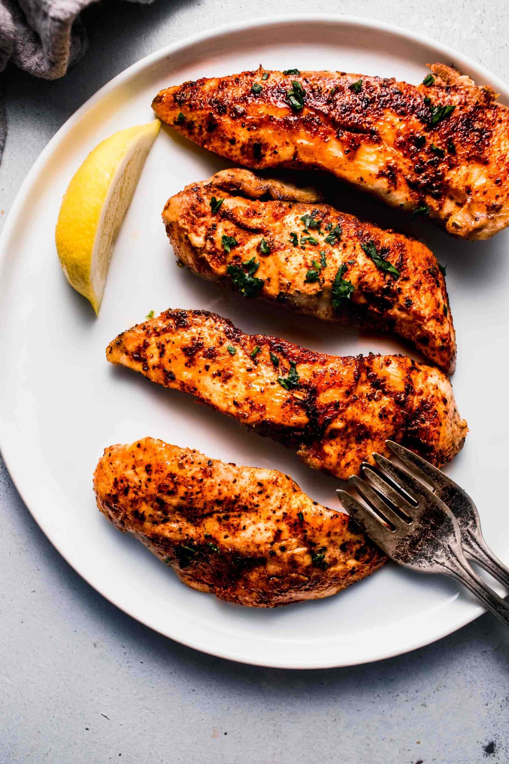 Sous vide chicken tenders on plate with lemon wedges.