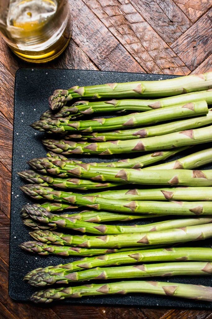 Uncooked asparagus spears on cutting board. 