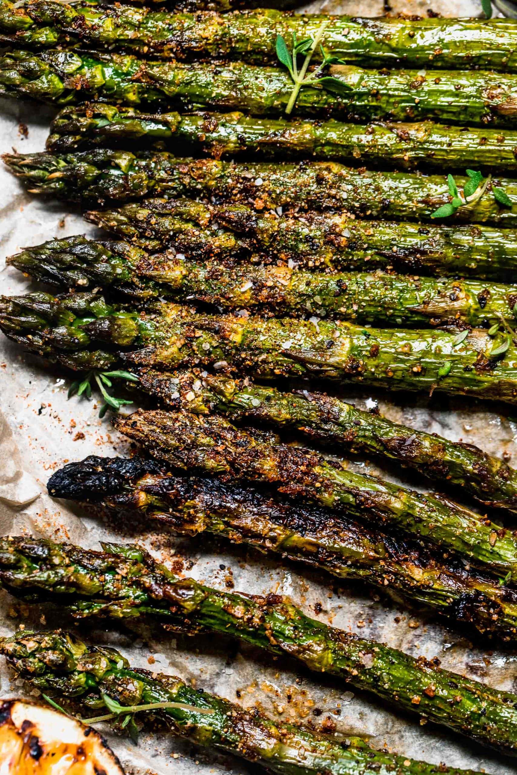 Smoked asparagus arranged on baking sheet with parchment paper.