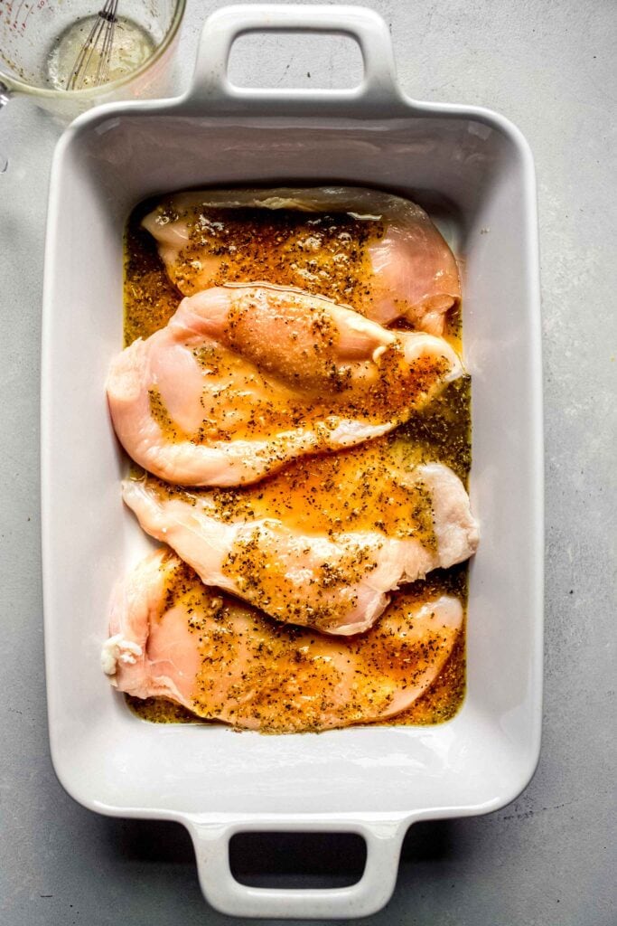 Chicken breasts marinating in baking dish.