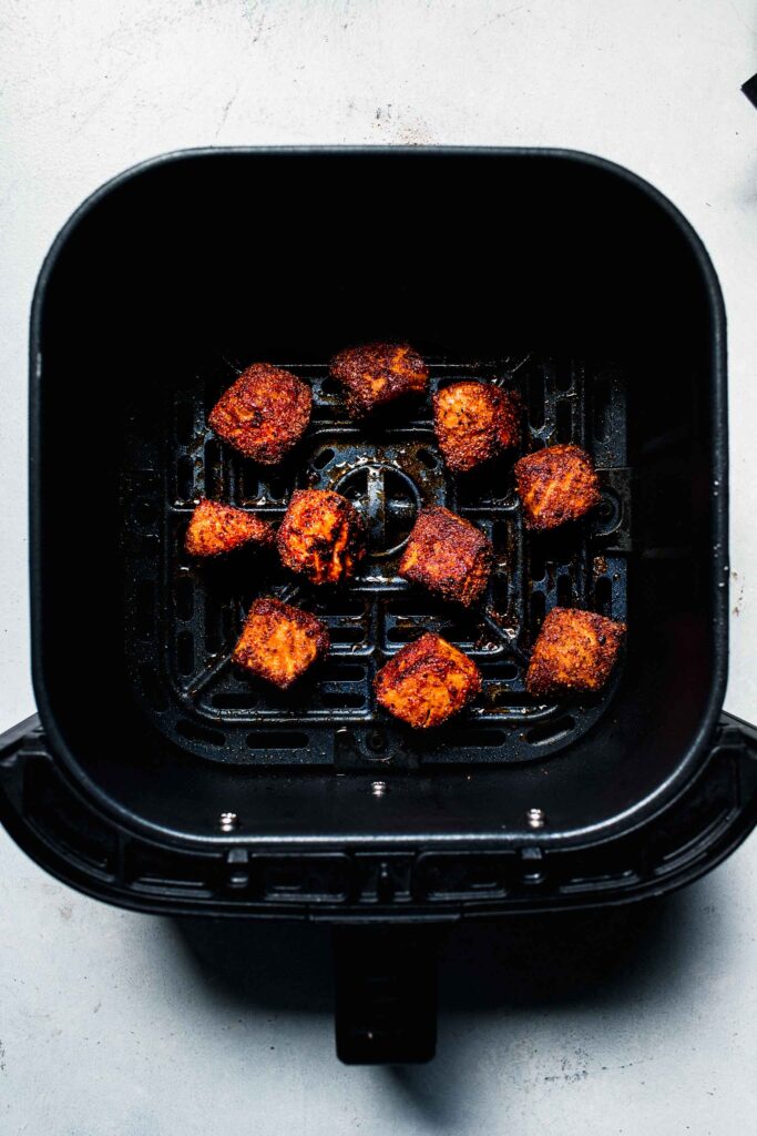 Cooked salmon bites in air fryer basket.
