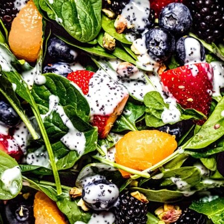 Overhead close up of prepared strawberry spinach salad with poppyseed dressing drizzled on it.