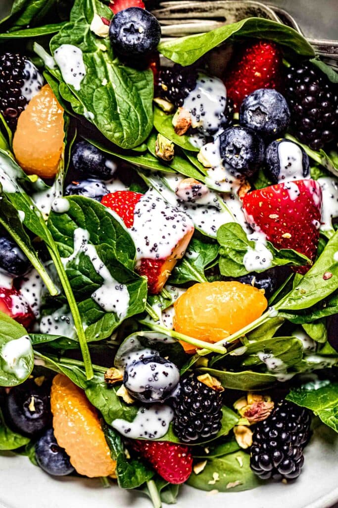 Overhead close up of prepared strawberry spinach salad with poppyseed dressing drizzled on it.