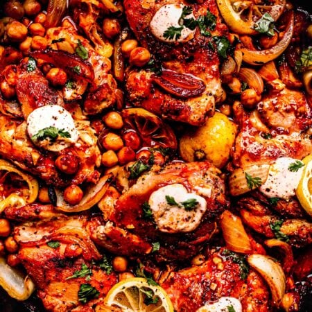 Harissa chicken in skillet topped with dollops of yogurt sauce.