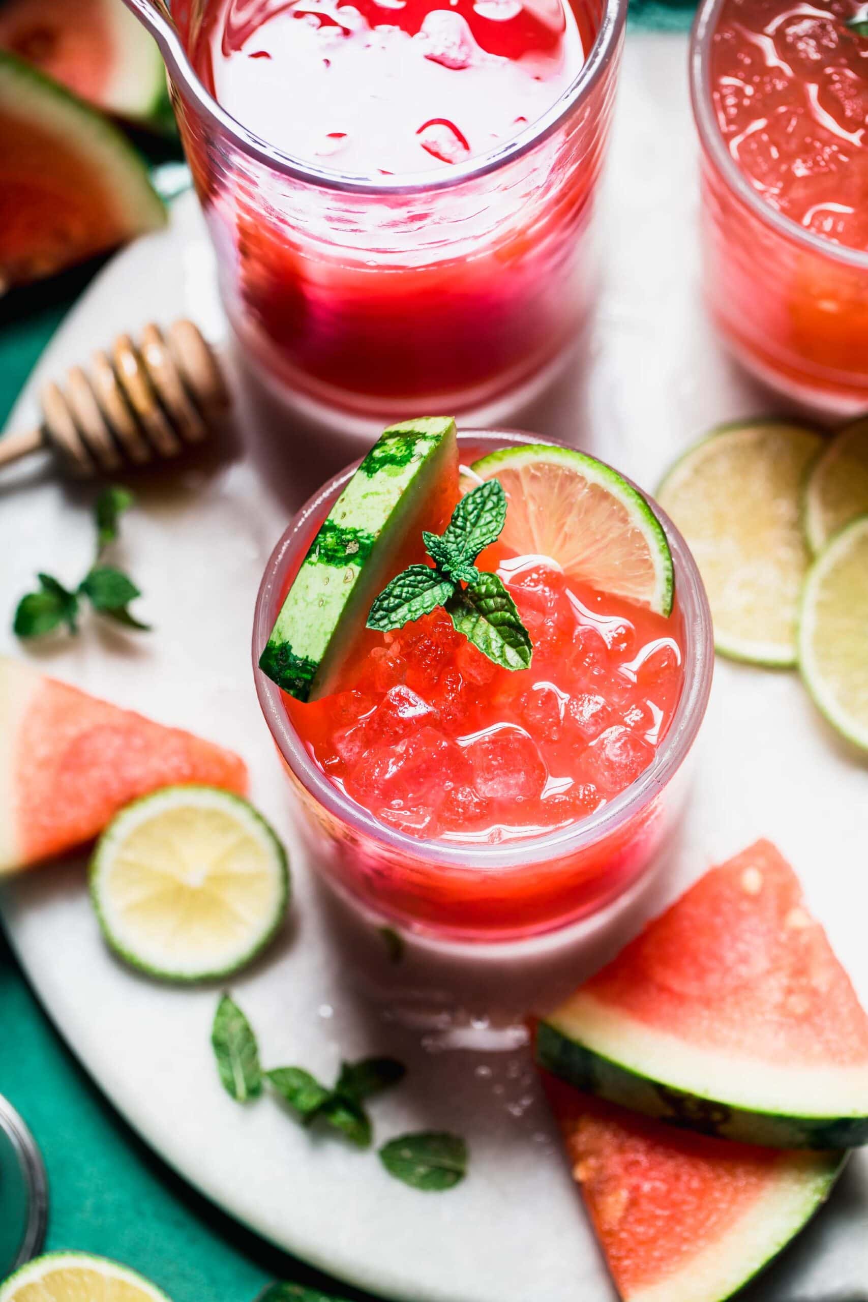 Watermelon cocktail on tray with watermelon wedges and lime wheels.