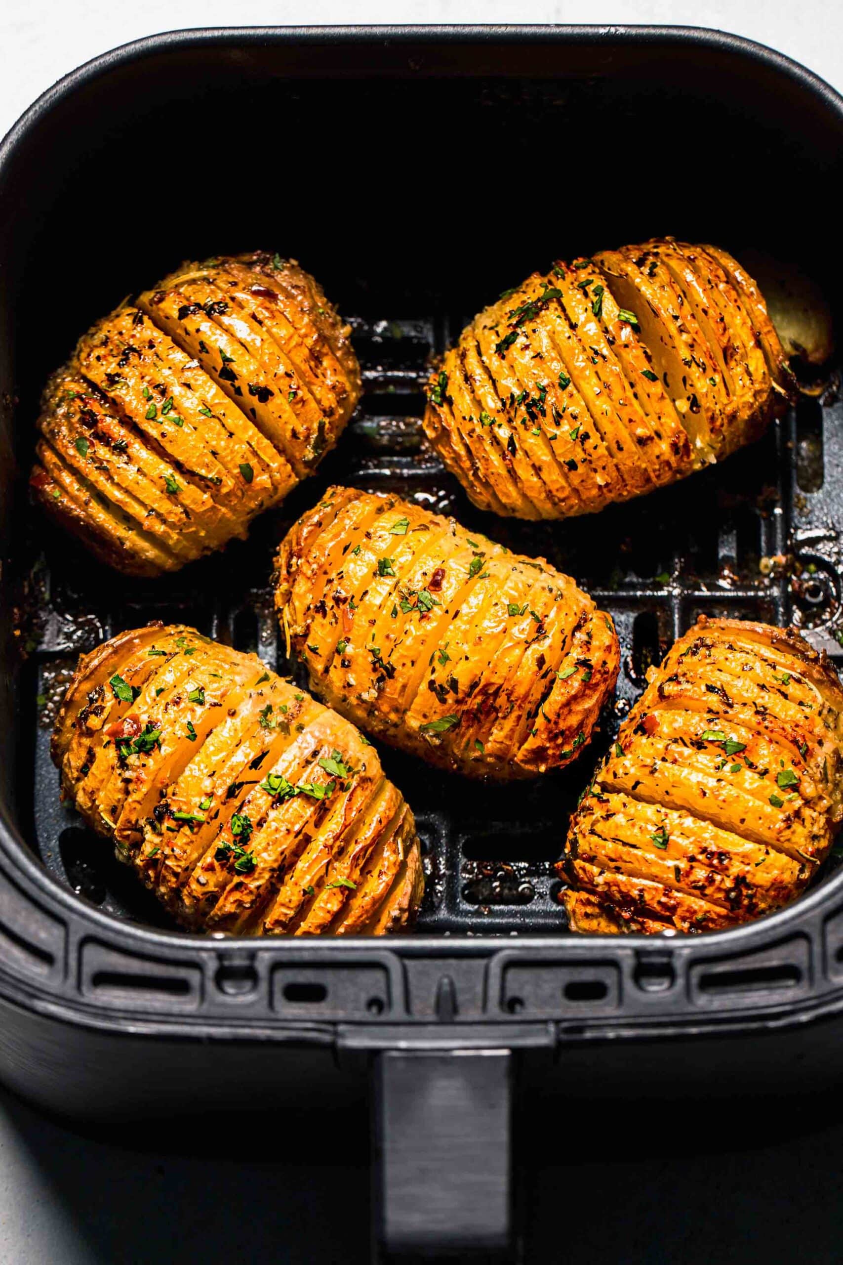 Cooked hasselback potatoes in air fryer basket.