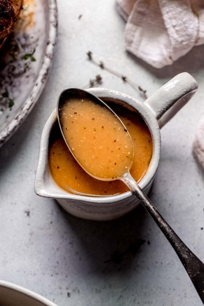 Spoon dipped into chicken pan sauce. 