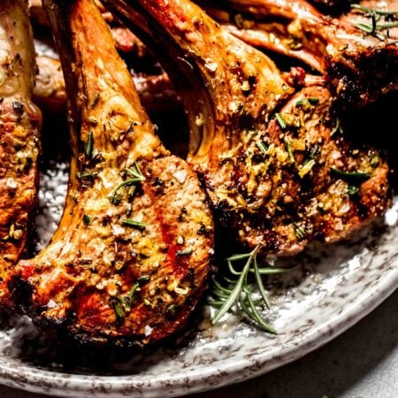 Prepared lamb chops arranged on grey plate.