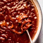 Onion gravy in large skillet with spoon.