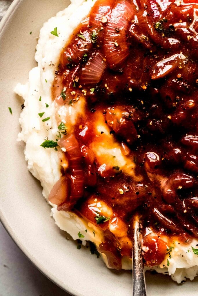 Onion gravy served over bowl of mashed potatoes. 