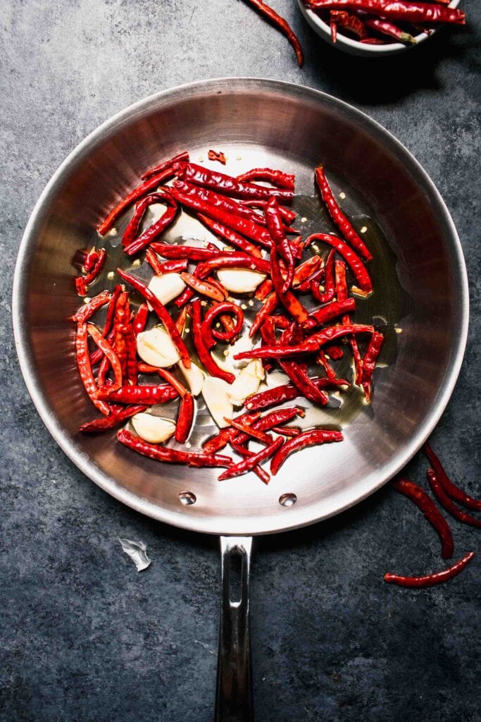 Peppers and garlic cloves in skillet.