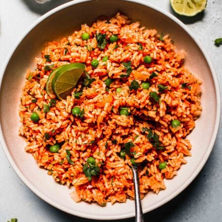 Mexican rice in white bowl with serving spoon.