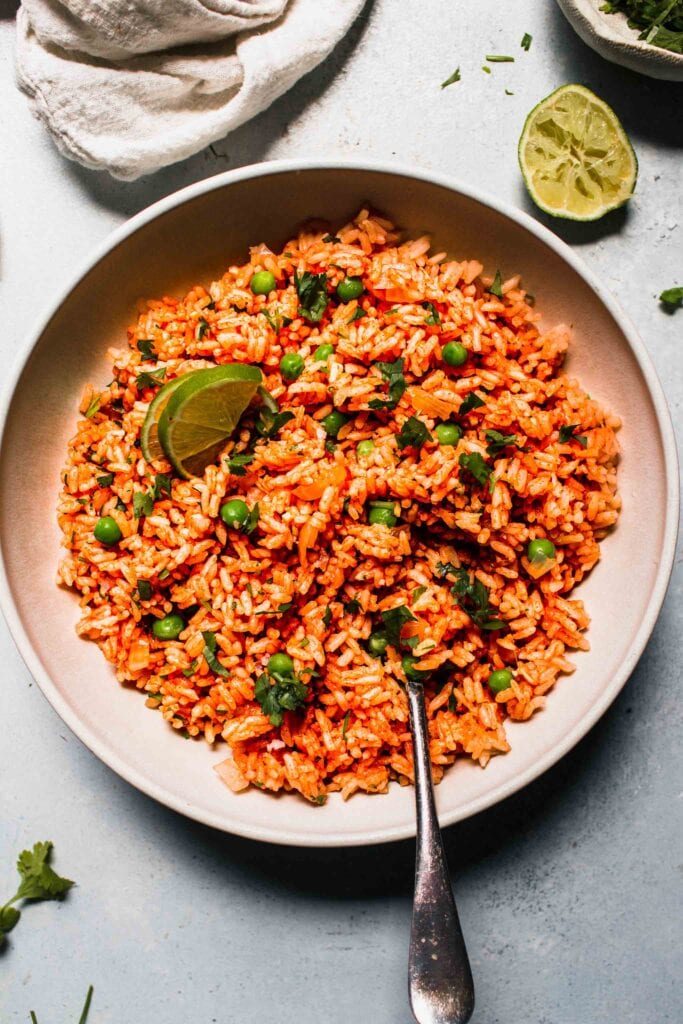 Mexican rice in white bowl with serving spoon.