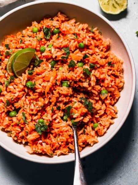 Mexican rice in white bowl with serving spoon.