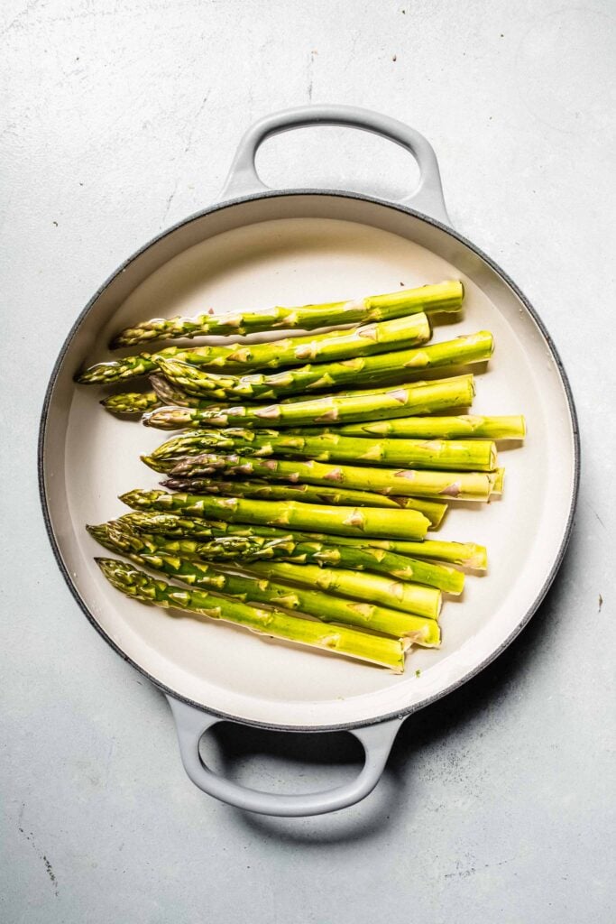 Uncooked asparagus in pot of water.