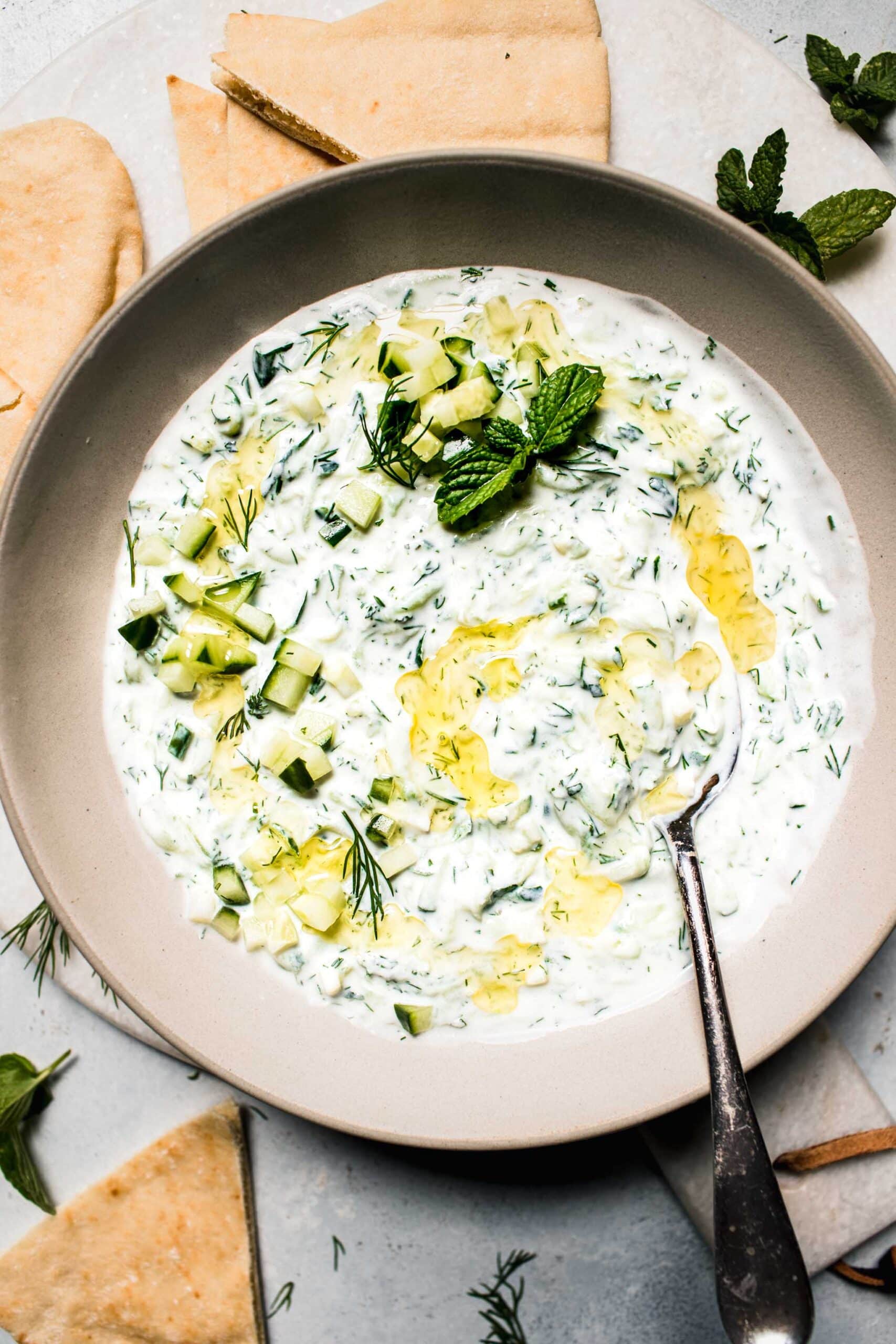 Overhead shot of prepared tzatziki sauce in bowl drizzled with olive oil.