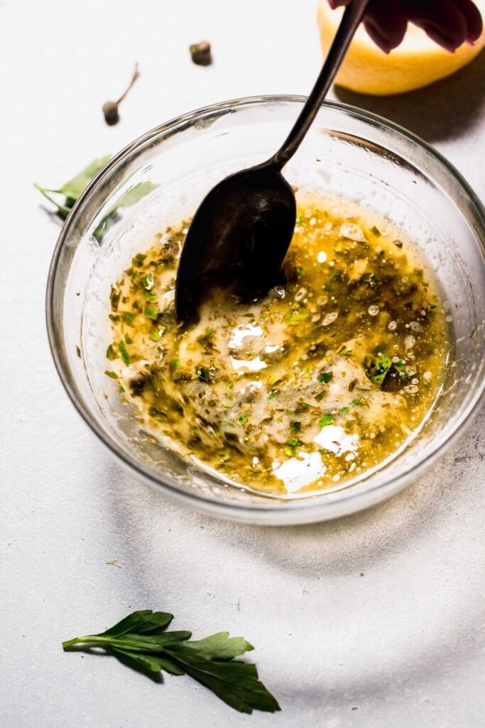 Bowl of lemon caper sauce being stirred. 