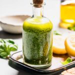 Hand putting cork on bottle of pesto salad dressing.