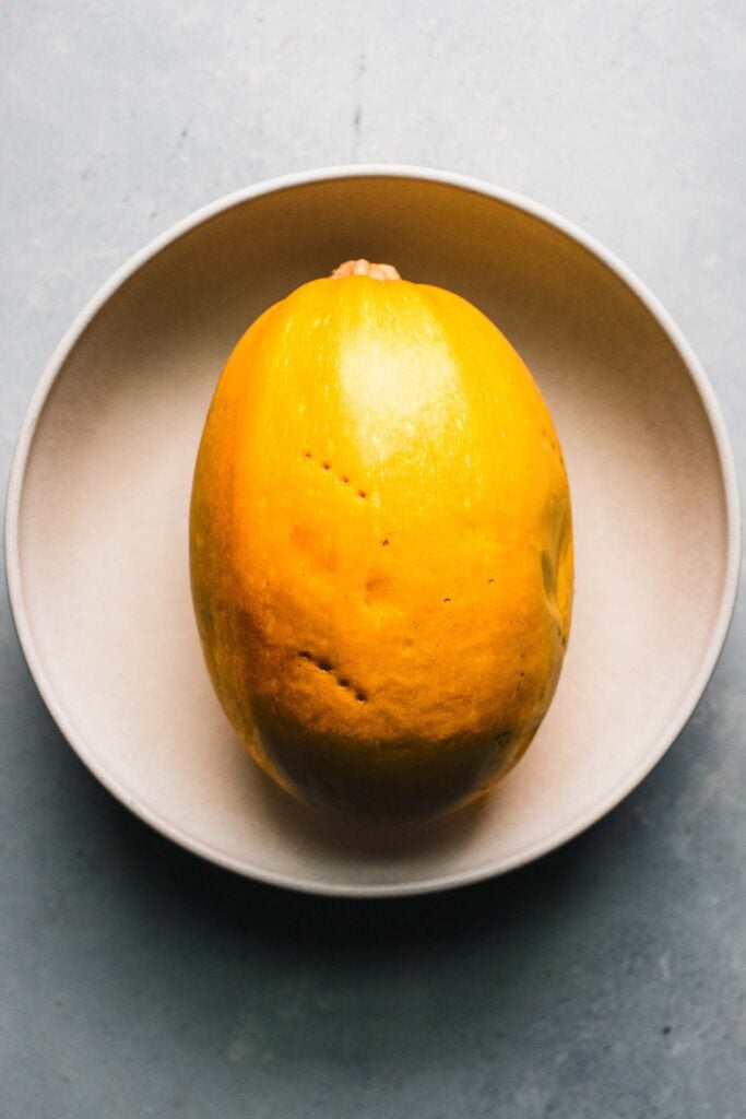 Spaghetti squash in bowl pricked with fork.