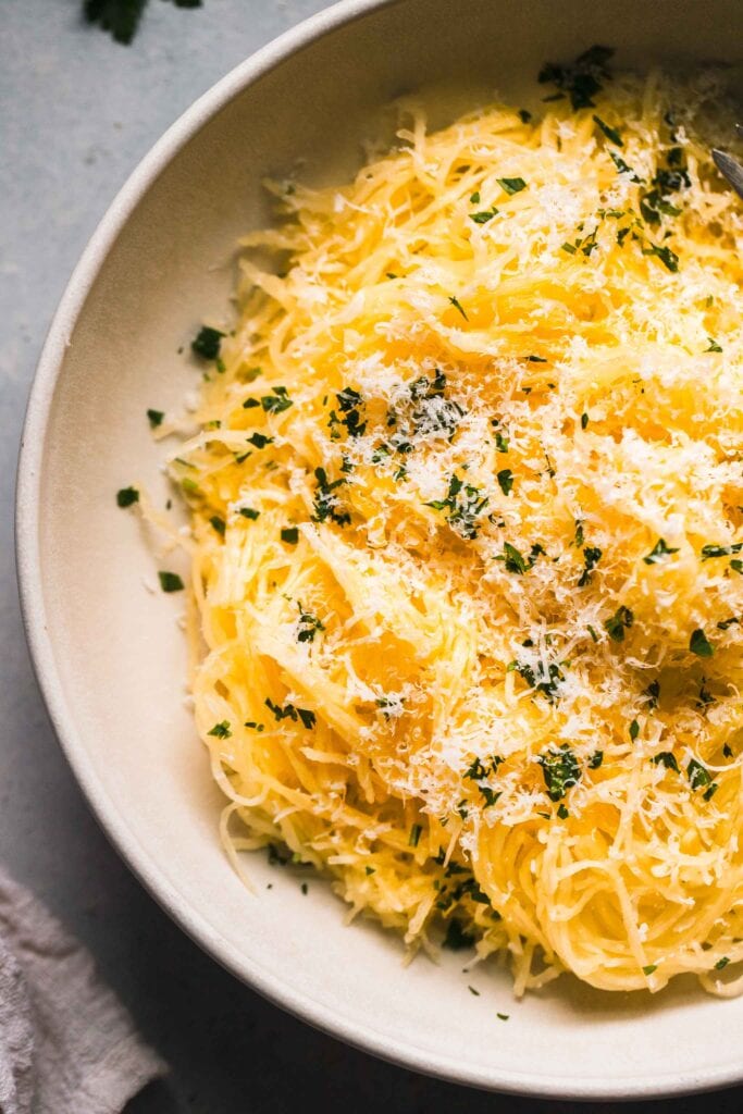 Prepared spaghetti squash in bowl topped with parsley & parmesan.
