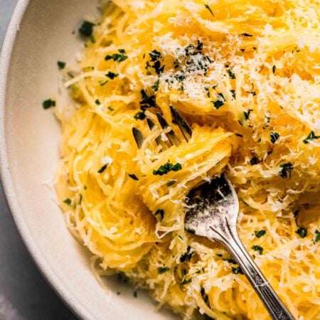 Prepared spaghetti squash in bowl topped with parsley & parmesan.