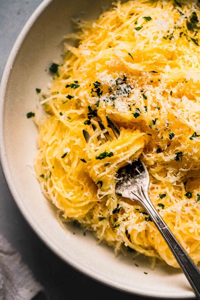 Prepared spaghetti squash in bowl topped with parsley & parmesan.