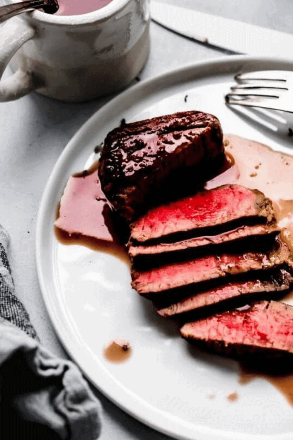 Sliced steak on plate with red wine sauce.