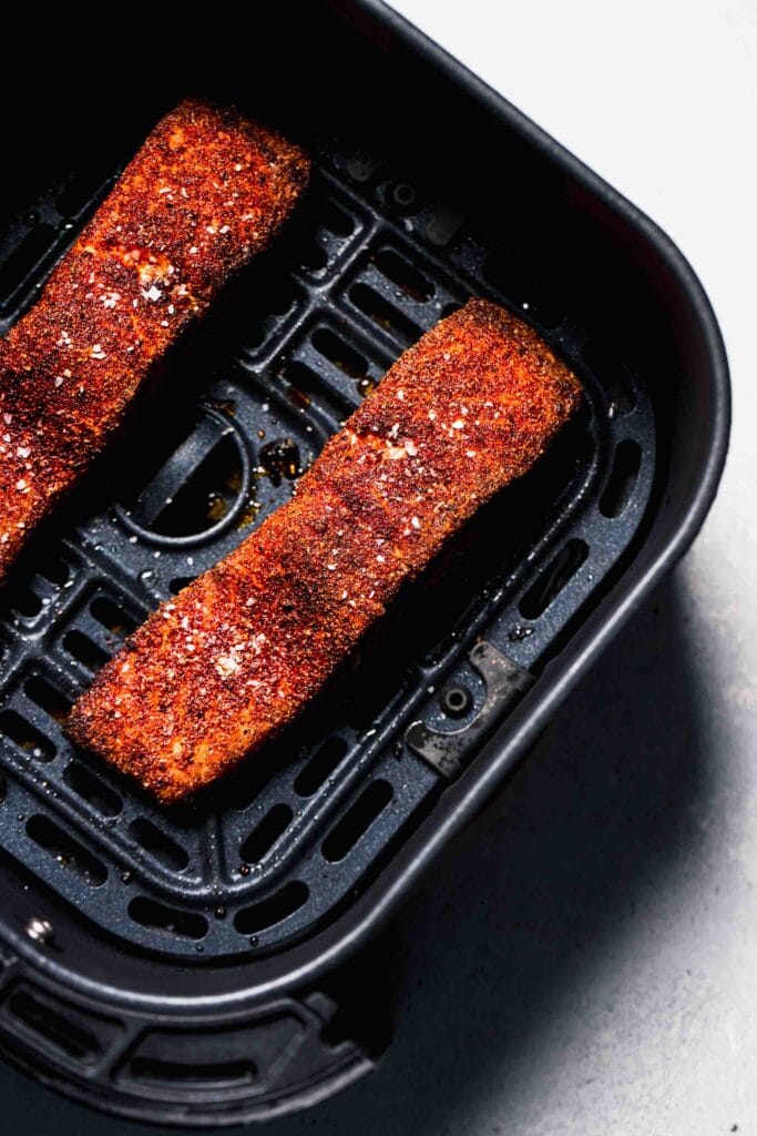 Cooked salmon filets in air fryer basket. 