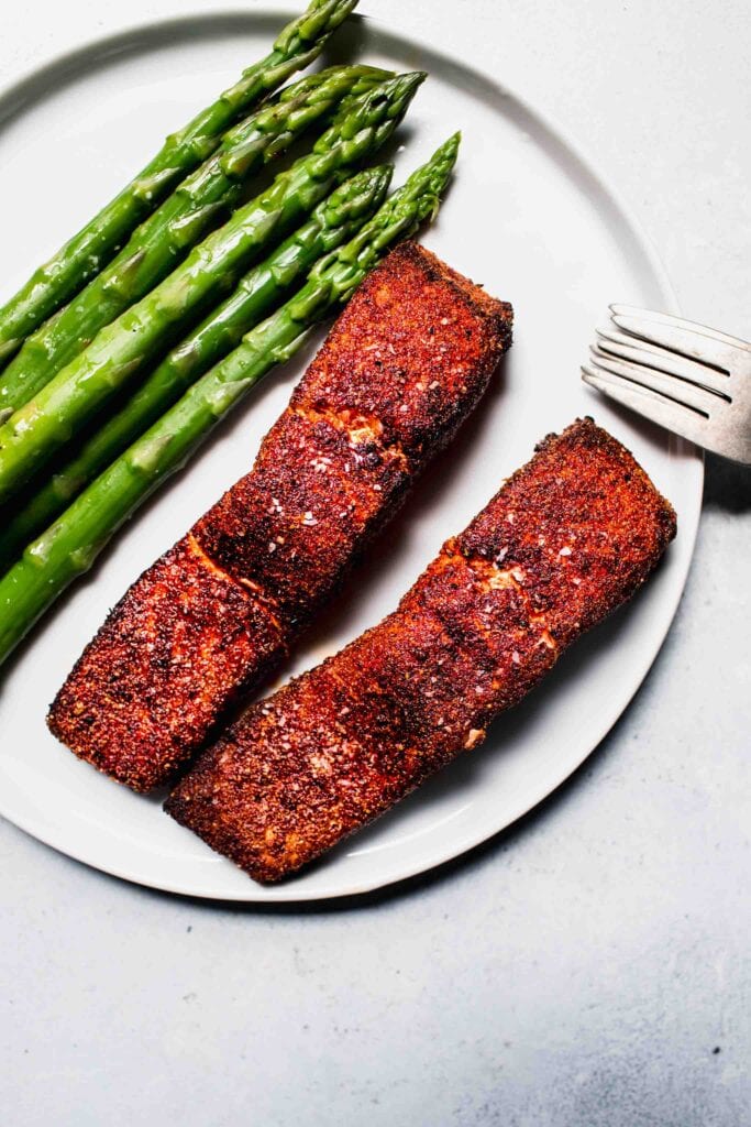Finished salmon filets on plate with asparagus. 
