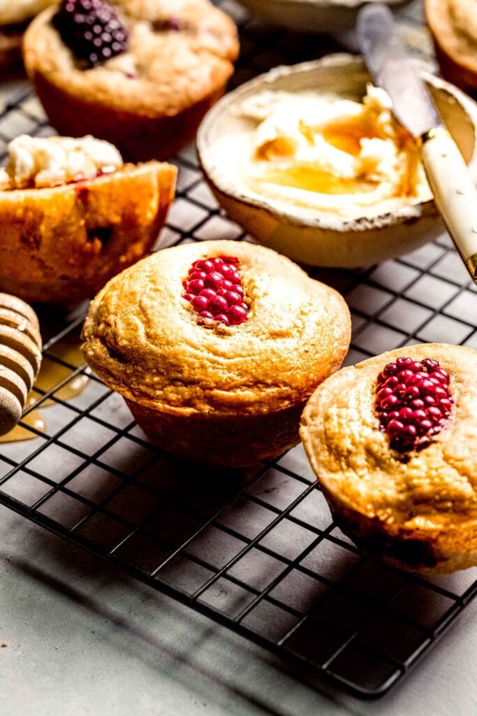 Side view of baked cornbread blackberry muffins on cooling rack. 