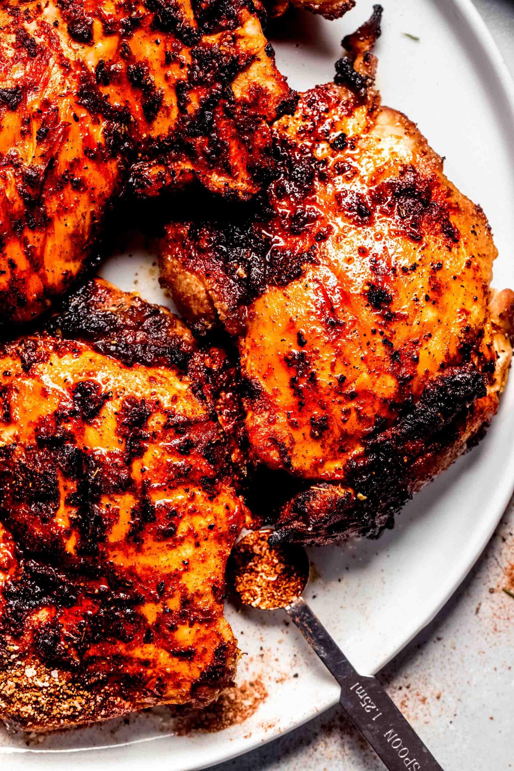 Traeger chicken thighs on plate with spoonful of dry rub.