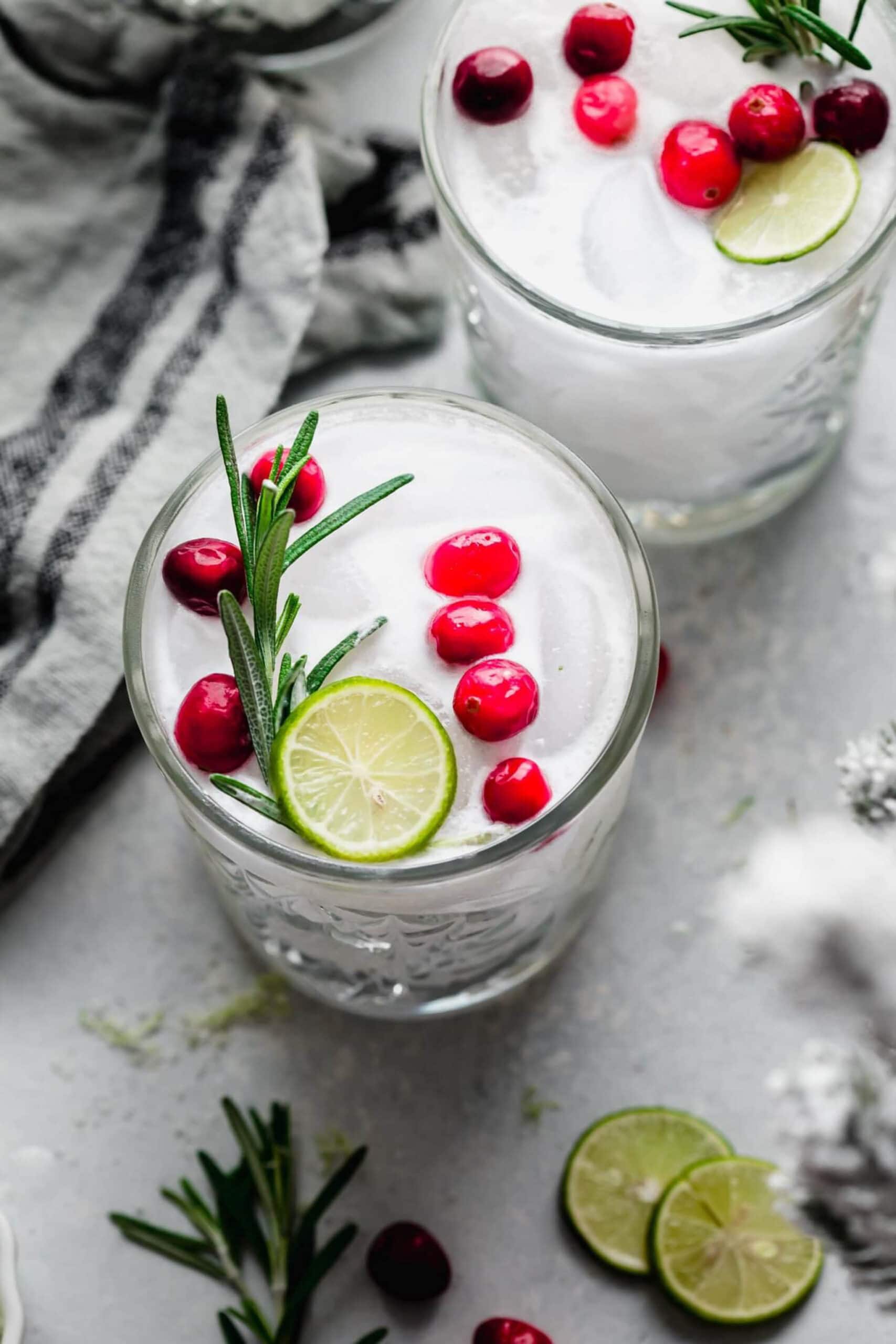 Overhead view of two holiday margaritas with cranberries and lime.