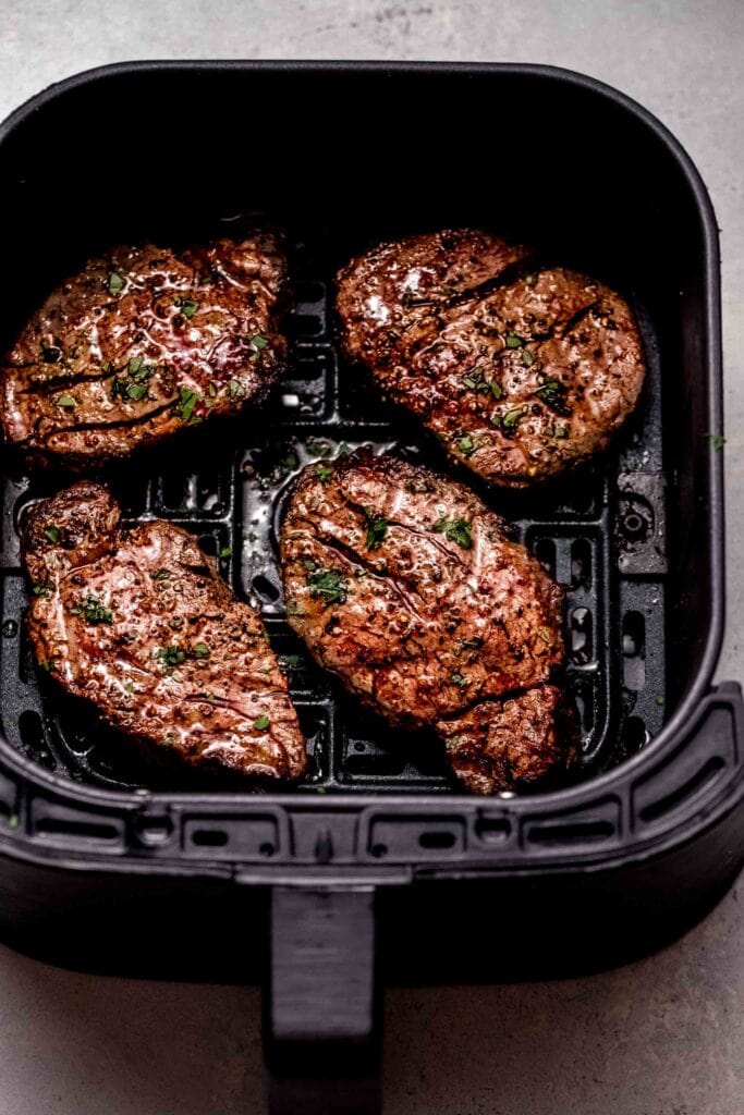 Cooked filet mignon in air fryer basket. 