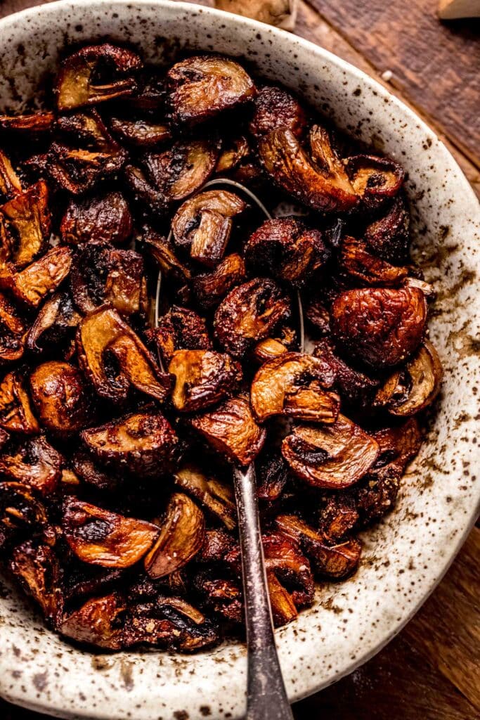 Crispy air fryer mushrooms in bowl with spoon.